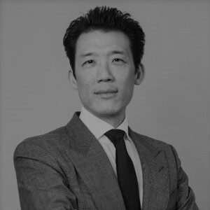 A portrait image of Jay Kwan in black and white. He is wearing a suit and tie.